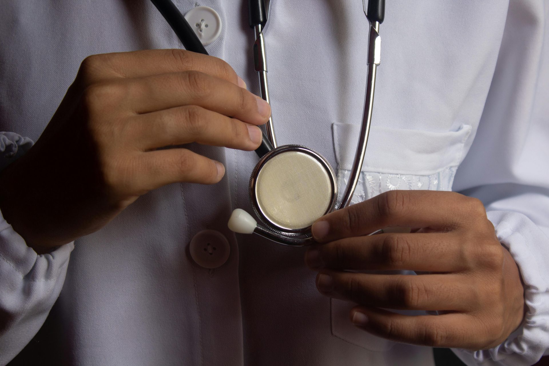 Eine Nahaufnahme zeigt einen Arzt mit einem Stethoskop, das symbolisch für Gesundheitswesen und ärztliche Praxis steht.